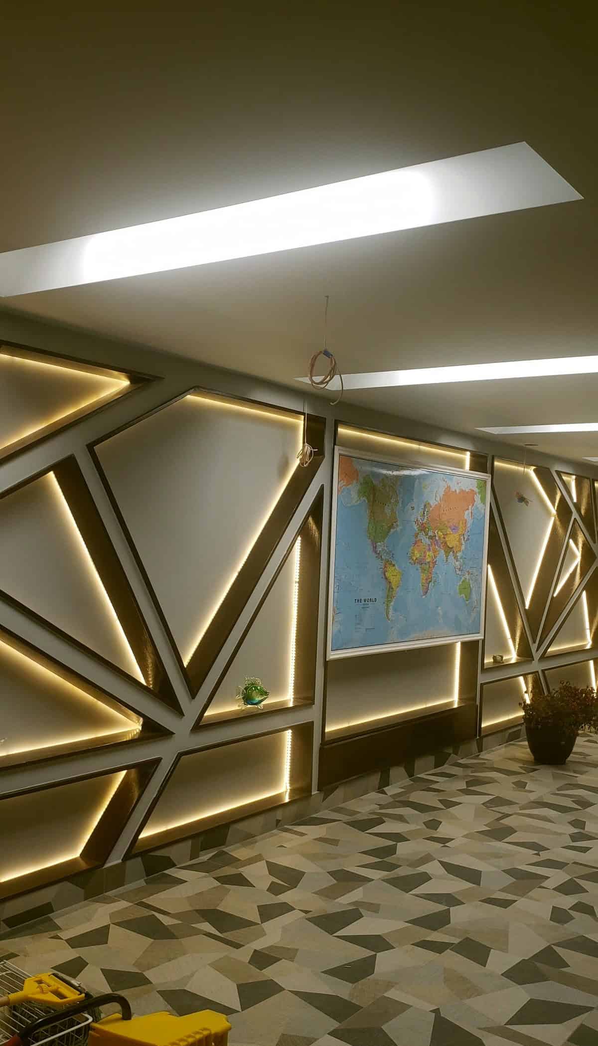 Basement hallway with custom LED backlit geometric wall panels and a geometric stone mosaic floor