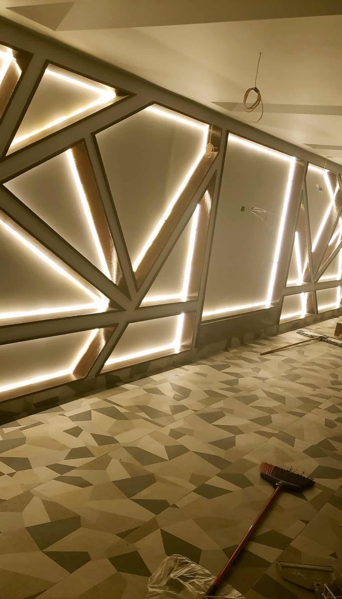 Custom LED backlit geometric feature wall at a staircase landing with a geometric stone mosaic floor