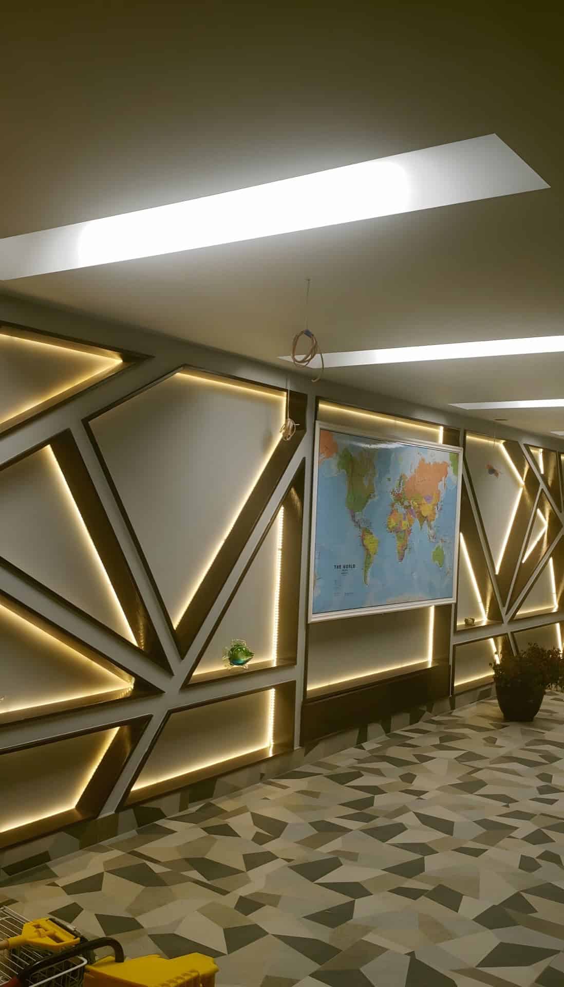 Basement hallway with custom LED backlit geometric wall panels and a geometric stone mosaic floor